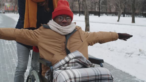 Cheerful Black Man on Wheelchair Enjoying Walk with Female Friend