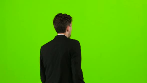 Businessman Is a Telephone Rings To Him and He Talks. Green Screen. Back View