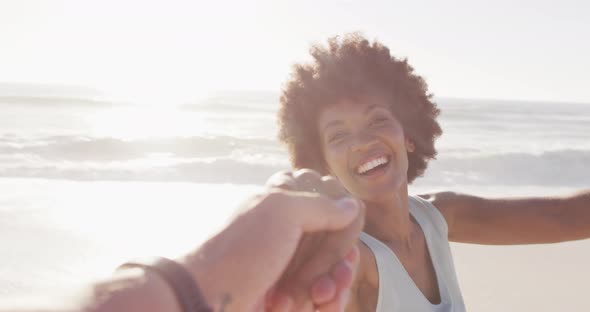 Portrait of smiling african american woman holding hand on sunny beach