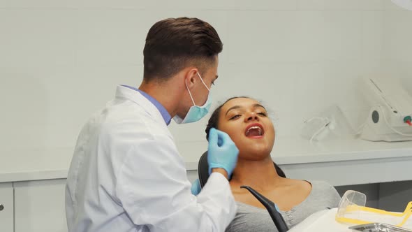 Cheerful Male Dentist Smiling While Examining Teeth of a Female Patient