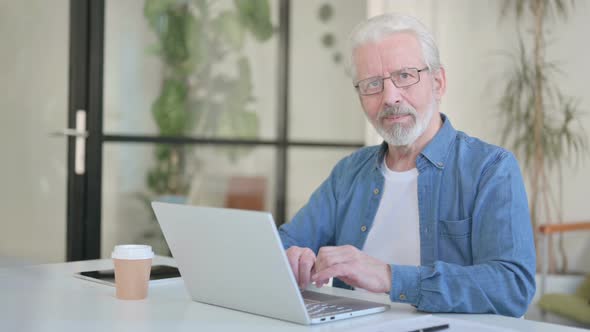 Senior Old Man Smiling at Camera While Using Laptop