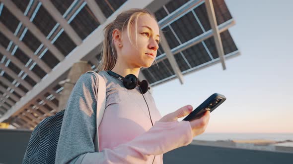 Young Beautiful Female in Sport Suit Standing Outdoors Using Phone