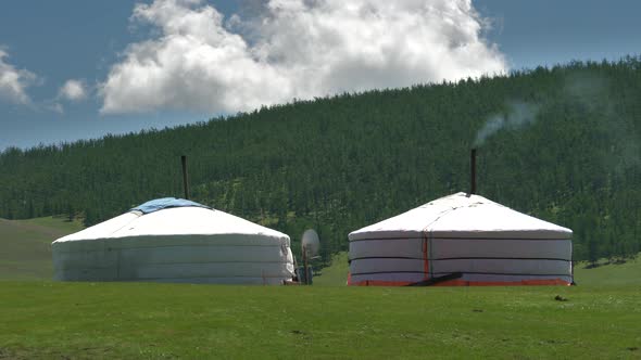 Mongolian tents with smoke from the chimney in front of the Taiga forests