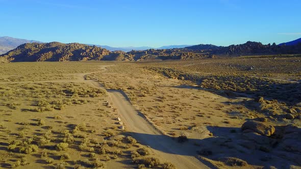 Scenic aerial drone view of dirt road and rocky desert landscape.