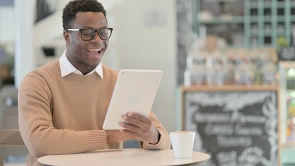 Video Call on Tablet By Creative African Man in Cafe