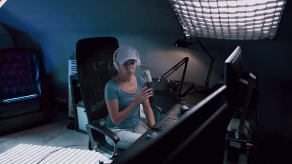 Beautiful Woman In A Cap And White Headphones Leads A Live Stream