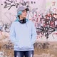 Blue haired teenage girl in light blue hoodie with headphones stays against graffiti wall - VideoHive Item for Sale