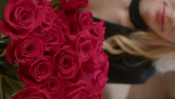 Vertical Video Close Up of Blonde Attractive Woman Smelling Bouquet with Red Roses