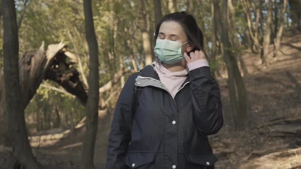 Happy Brunette Girl Taking Off Face Mask and Smiling To Sun. Portrait of Pretty Caucasian Woman