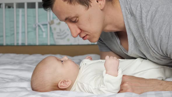 Young Father Speaks to Baby Girl Holding Tiny Child Hand