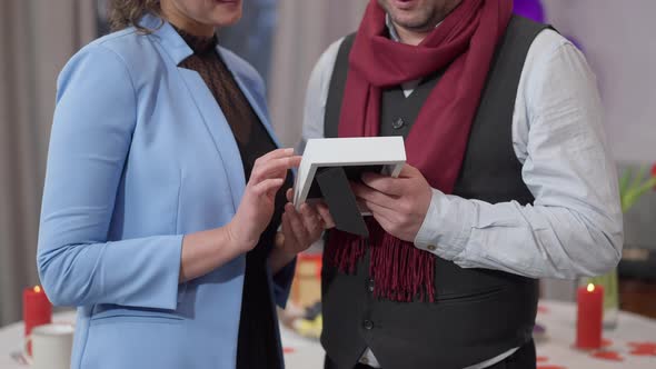 Unrecognizable Smiling Couple Admiring Photo Hugging Indoors