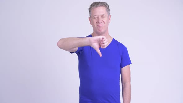 Serious Mature Man Giving Thumbs Down and Showing Stop Gestures