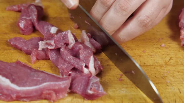 Closeup of a Cook Slicing Red Meat on a Kitchen Board