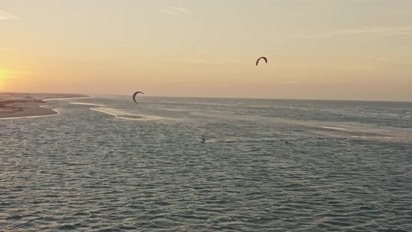Drone tracking Guriu kite surfers playing in ocean horizon sunset glow