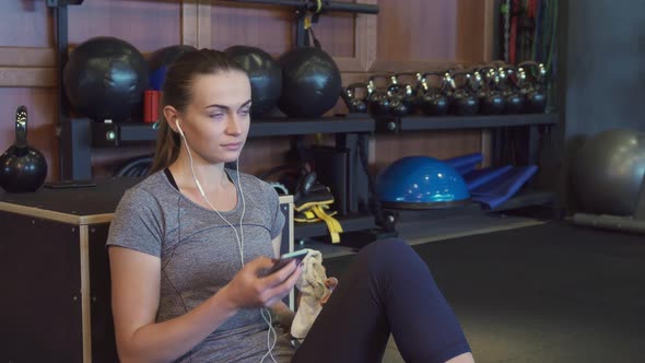 The Girl Is Listening To Music on Headphones During a Break Between Training Sessions 