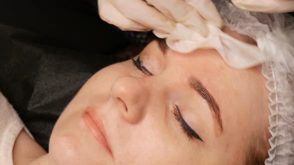 The Cosmetologist Removes the Remains of the Coloring Pigment From the Skin of Eyebrows with a