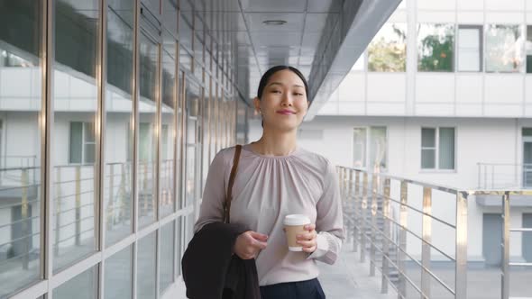 Asian Businesswoman Going to Work Drinking Coffee Outside Office Building