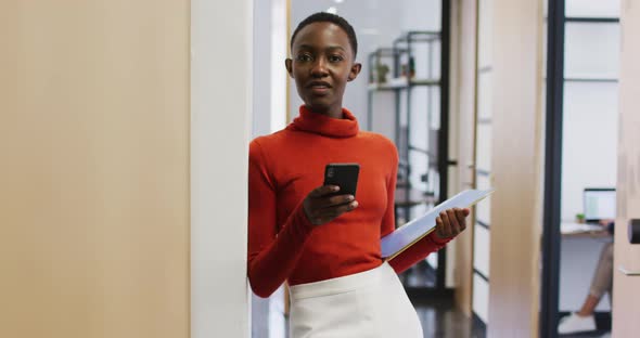 Portrait of african american woman smiling while using smartphone at office