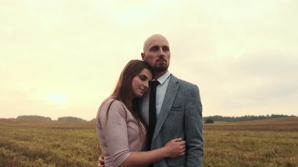 A Young Couple in Love is Walking in a Field Soft Sunlight in the Background