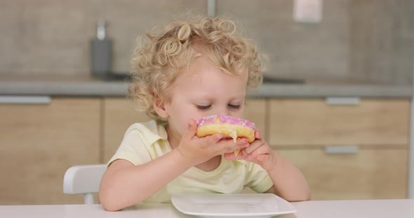 Adorable Little Girl Takes a Donut From the Plate Bites and Puts It Back to the Plate While Sitting