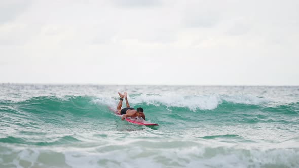 4K Asian senior man surfing in the sea at tropical beach on summer vacation