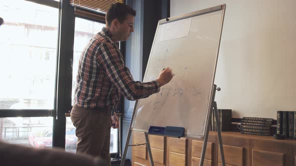 Two Businessmen Write on a Flipchart