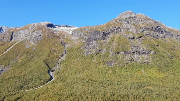 Impressive Norwegian mountains, green forest valley, blue sky