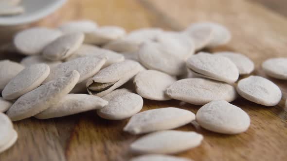 Roasted salted white pumpkin seeds. Falling in slow motion from a white ceramic cup