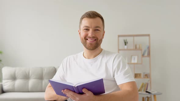 Cheerful Happy Disabled Person Reading a Book in a Wheelchair and Looking at Camera