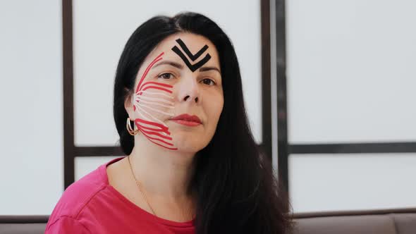 Portrait of adult woman with kinesio tapes on cheek and forehead, kinesiology facial lifting therapy