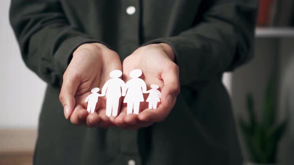 Paper Family Hold The Hands Of A White Mixed Race Woman. Hands Close Up Life Saving Insurance