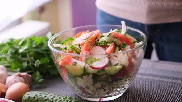 Woman Adding Salt and Spices Into Mixed Salad of Vegetables  Tomatoes Cucumbers Onion Parsley