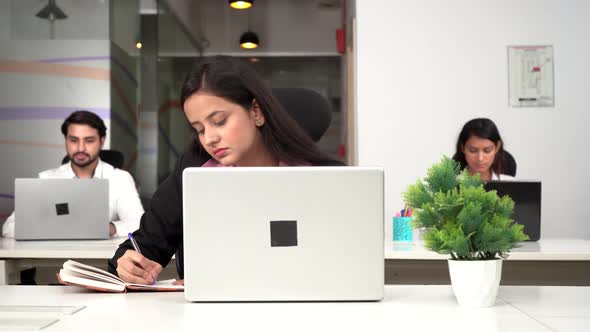 Indian corporate girl writing notes in an office