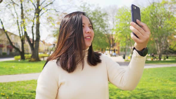 Asian black straight woman with happy face walking at the park and taking vdo call