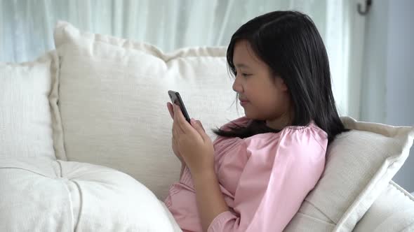 Beautiful Asian Girl Playing Smartphone  Sitting On A Sofa In The Living Room At Home Slow Motion