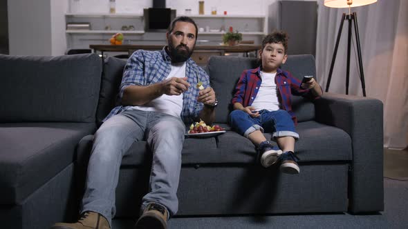 Relaxed Father and Son Watching Movie on Tv