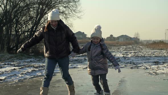 Young Woman with a Daughter of 78 Years Old Glide Merrily on the Ice of a Frozen Lake