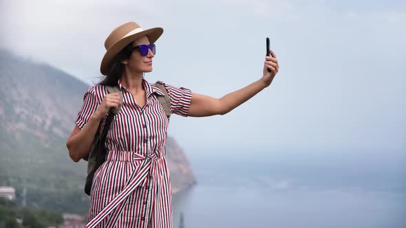 Elegant Female Smiling Posing on Top of High Mountain Over Sea Taking Selfie Use Smartphone