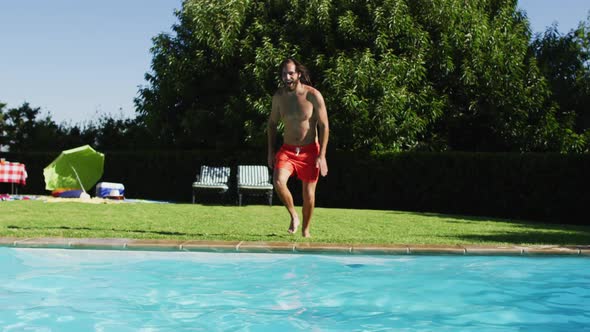 Caucasian man having fun jumping into a swimming pool