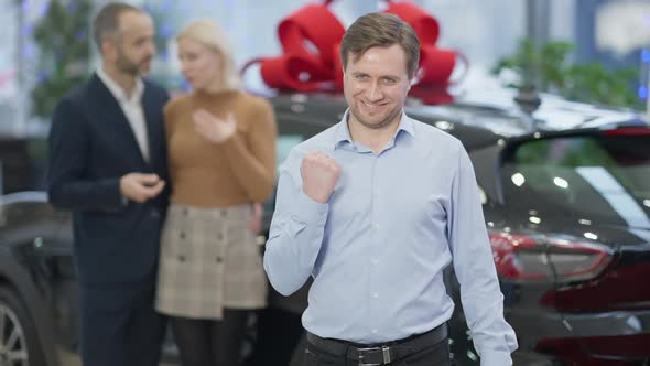 Satisfied Caucasian Car Dealer Showing Yes Gesture in Slow Motion and Smiling Looking at Camera with