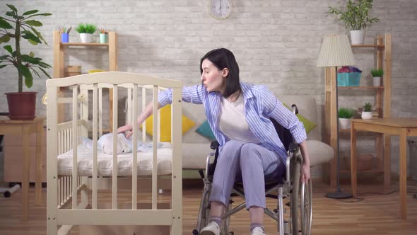 Young Woman Mother Disabled in a Wheelchair in the Nursery