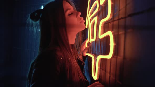 Young Beautiful Confident Caucasian Girl Posing at a Party Near Neon Lamps