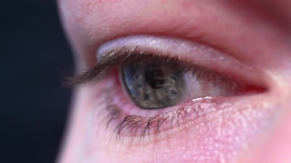 Reflection of screen on person's blue green eye in dark room 9