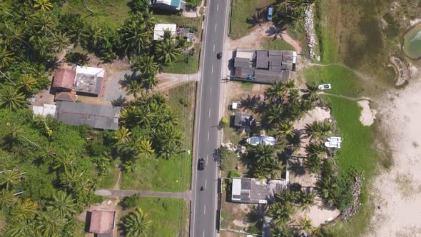 Drone shot following a car and motorbike along road on sunny day in Sri Lanka