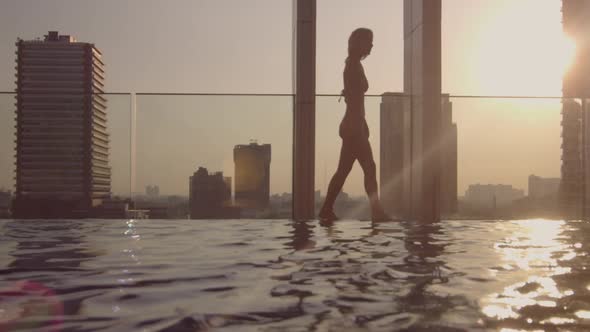 Woman In Bikini Walking Along Side Of Hotel Infinity Pool