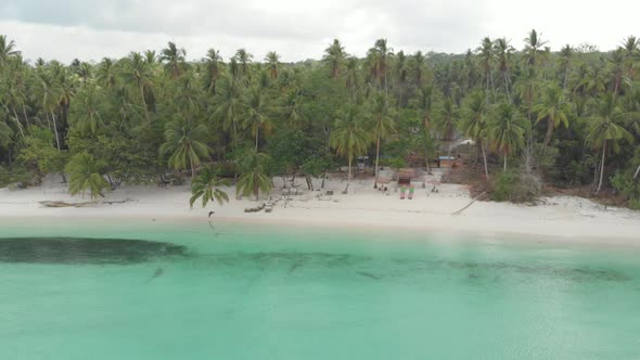 Aerial: flying over white sand beach tropical sea Wab village Maluku Indonesia