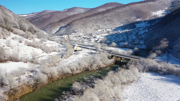 Mountain Winter Road That Crosses the River Aerial View