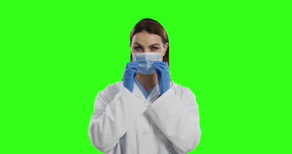 Caucasian female doctor wearing face mask on green screen background