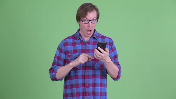 Happy Young Hipster Man Using Phone and Pointing Up