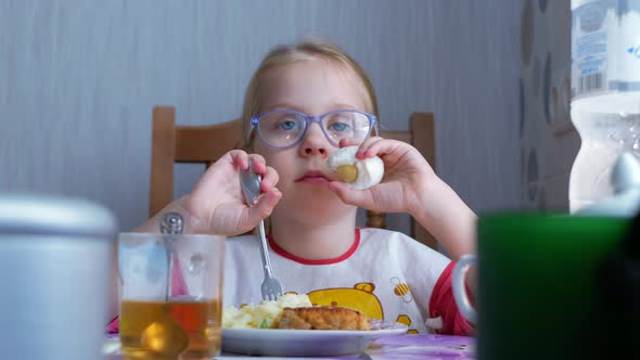 Little Girl Eating a Boiled Egg at Kitchen